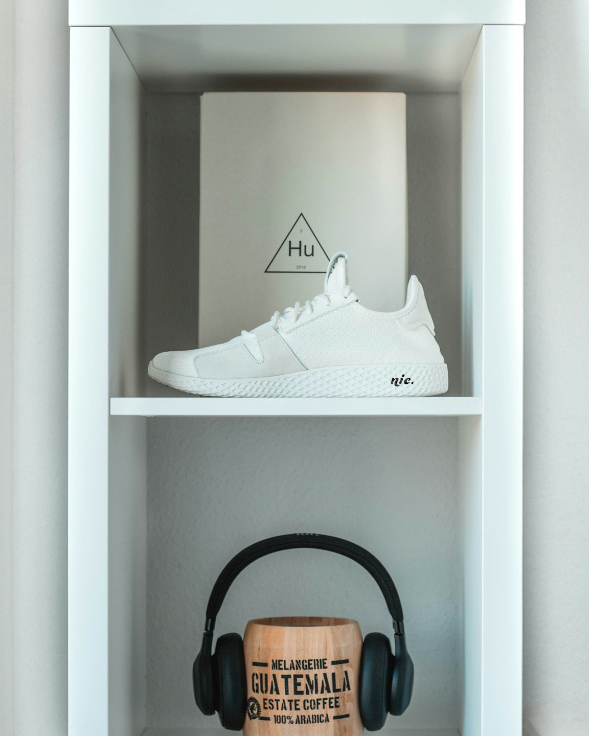 White sneaker and headphones displayed on shelves.