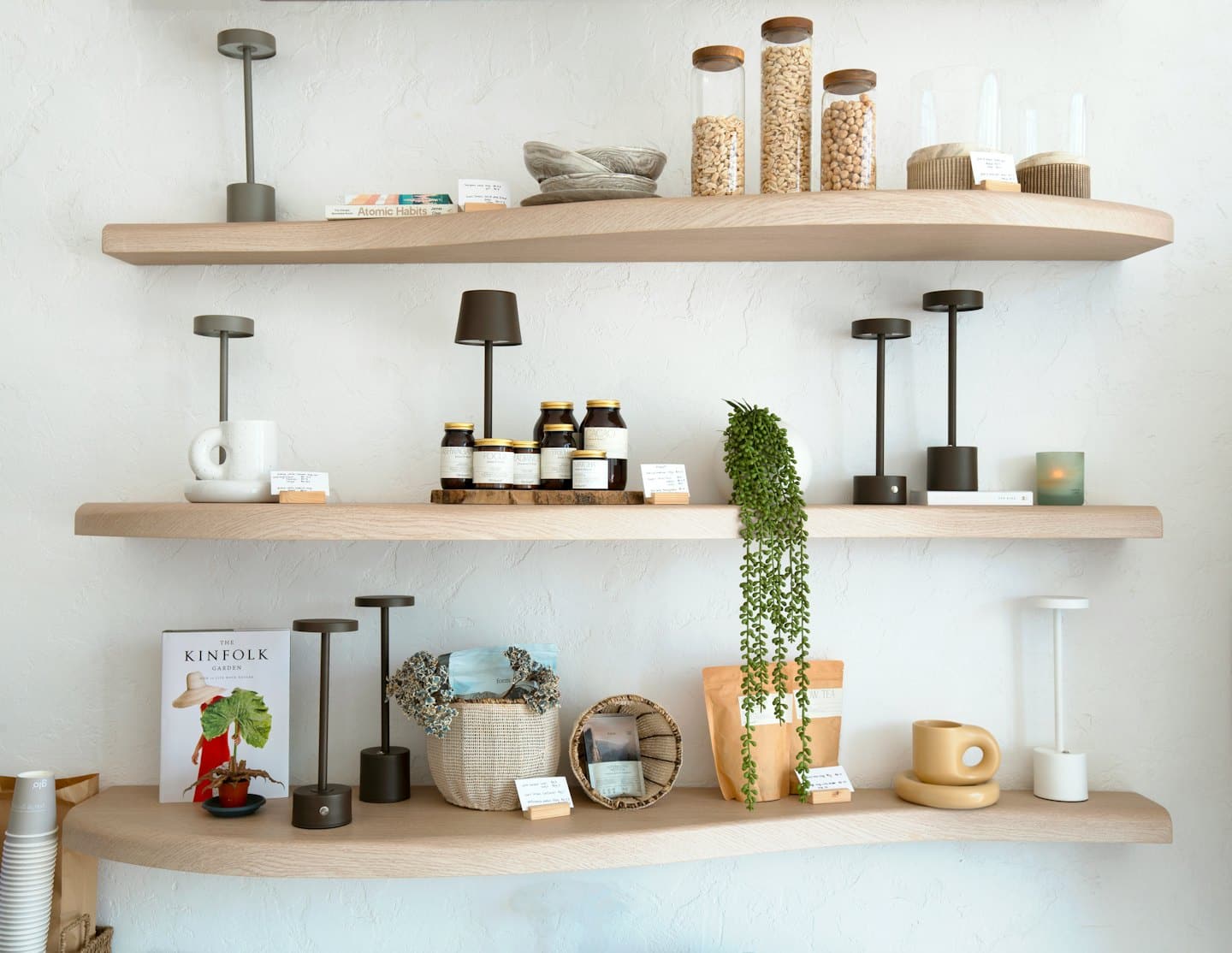 Wooden shelves on a white wall display retail goods.
